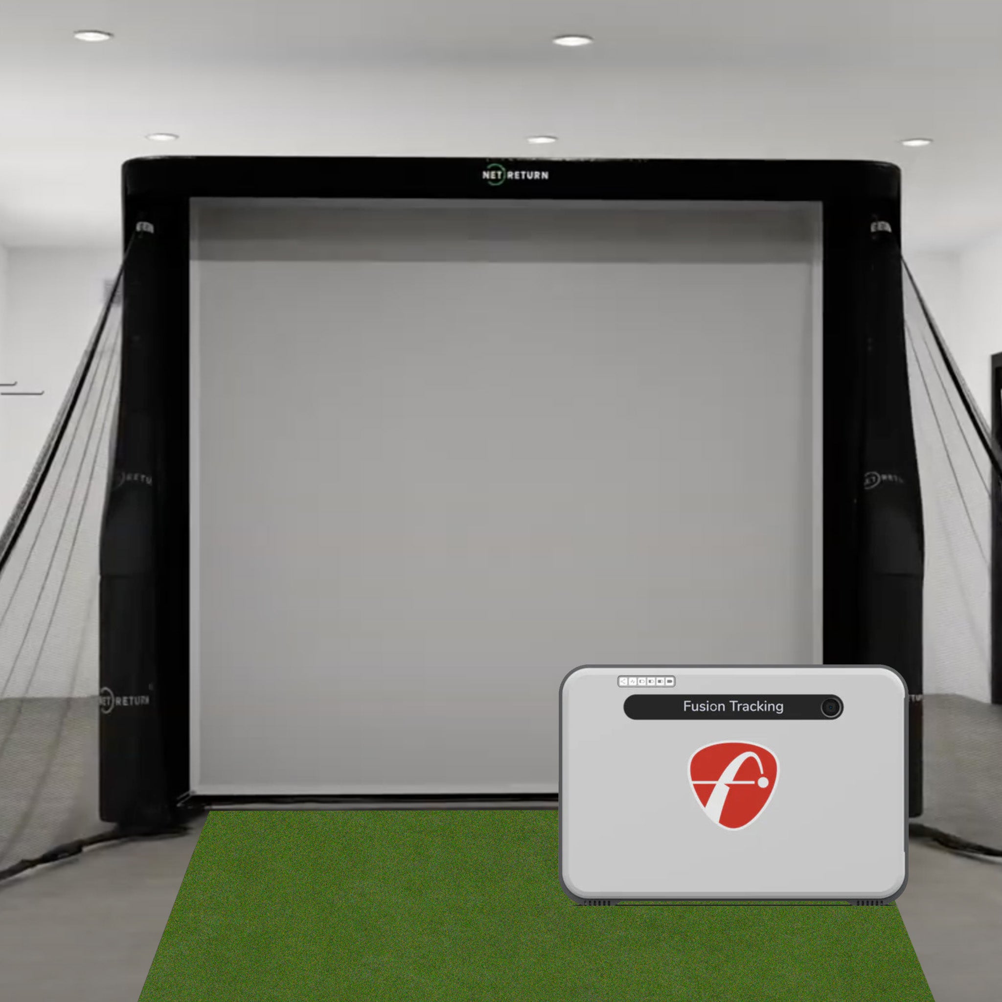 Indoor golf simulator setup with a screen, side nets, and a branded control device on a green turf surface.